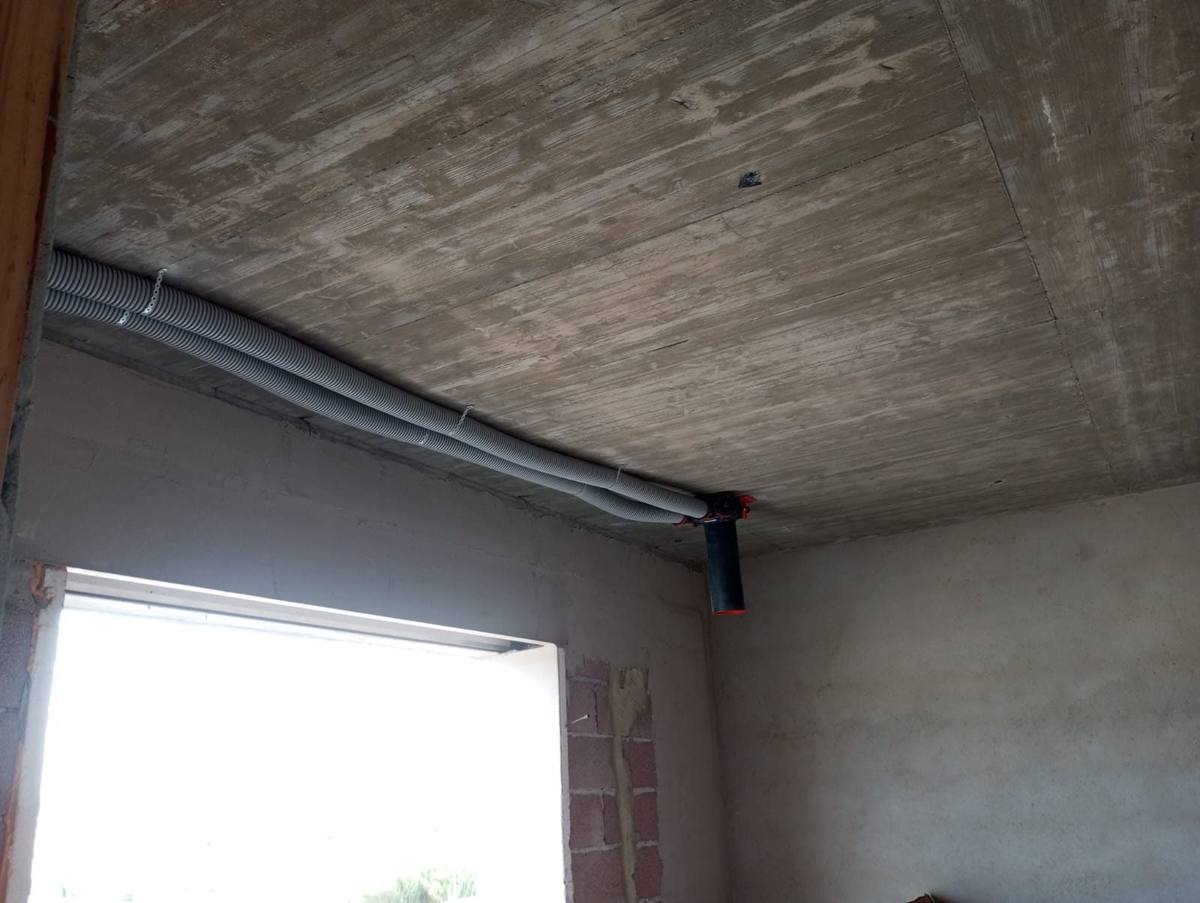 Condutas de ventilação e tubagem no teto de um corredor em obra