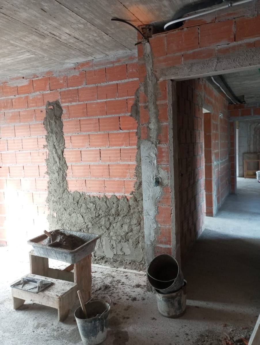 Reboco de parede em alvenaria com talocha e tabuleiro de argamassa