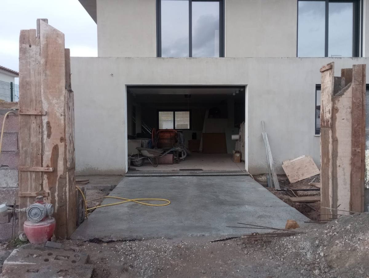 Entrada e fachada de uma moradia em obra, com betão recém-colocado