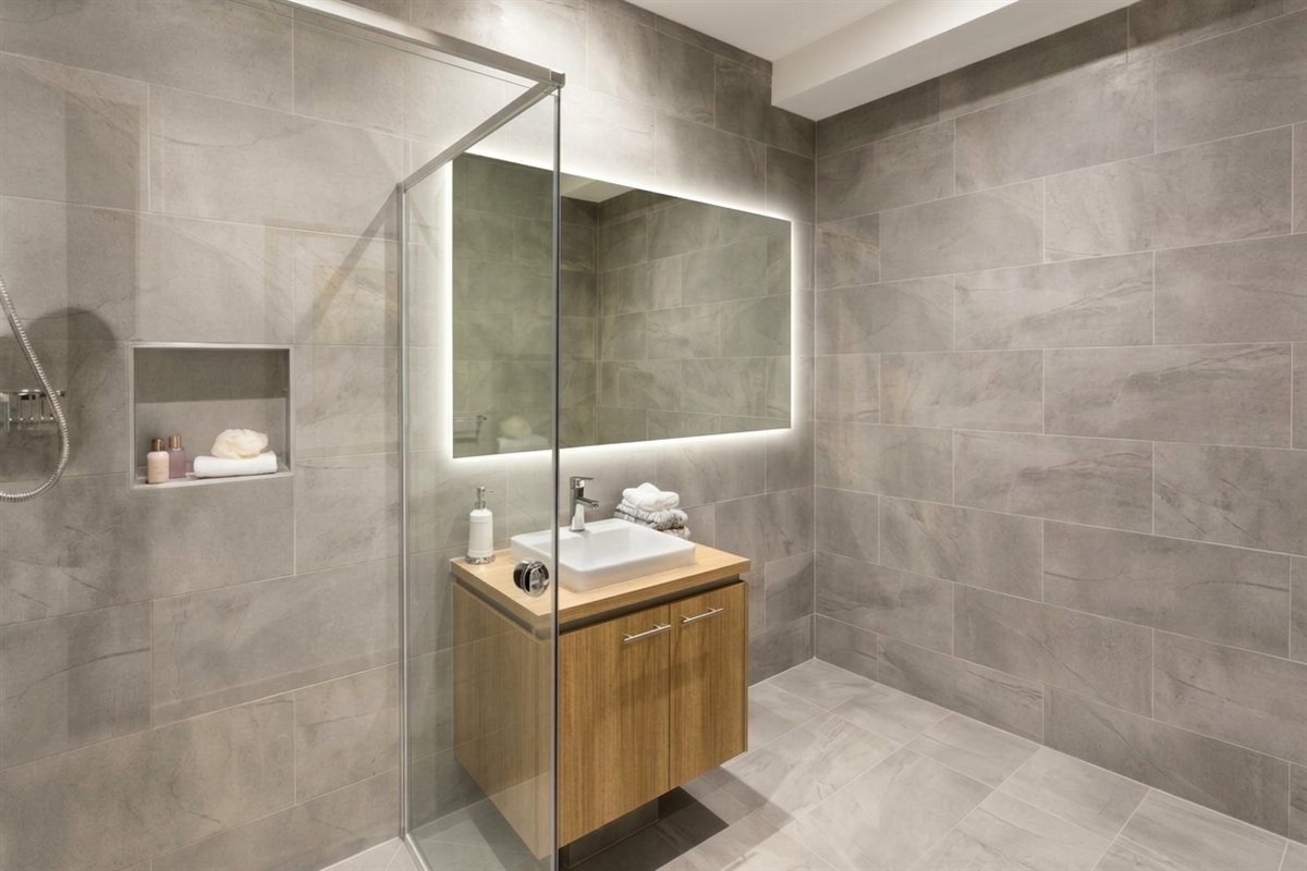 Casa de banho com duche de vidro, espelho com luz LED e móvel suspenso em madeira